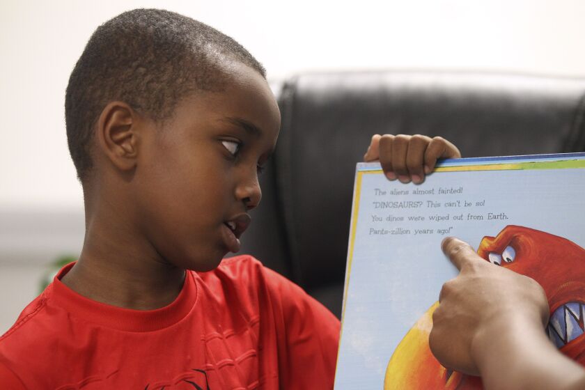 Ahmed Hassan, 7, reads aloud as he and Jerry Riggings Jr. 16, son of the the owner of Urban Barber College, read "Aliens Love Dinopants" to children during the Summer Time is Reading Time in the Diamond, a children's book read-aloud, at Urban Barber College on Wednesday, July 10, 2019 in San Diego, California.