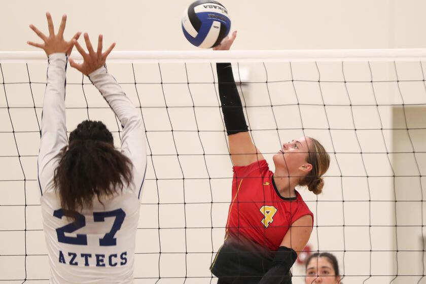 Estancia's Jenna Schroder (4) tips the ball over Raellie Faatuga during girls' Coast League Championship game against La Quinta on Tuesday.