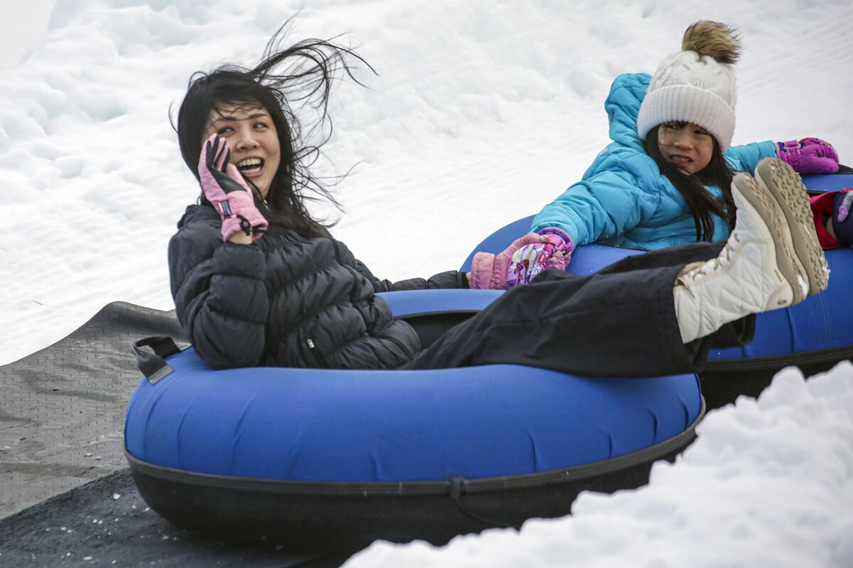 A woman and a little girl in blue inner tubes in the snow