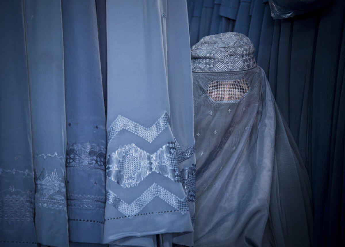 An Afghan woman peers through the eye slit of her burqa as she waits to try on a new burqa in a shop in Kabul, Afghanistan. Human Rights Watch says Afghan women are increasingly being jailed for what are considered "moral" crimes.