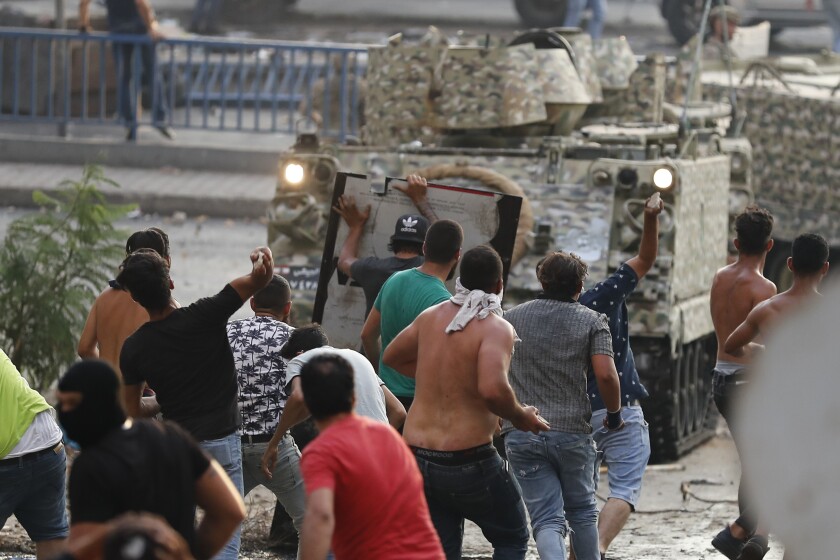 A crowd of men charges forward, some throwing rocks.