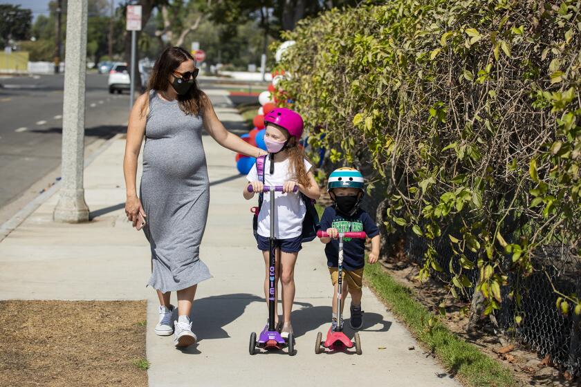 Danielle Hodge, walks with her daugther Isla, 6, and son Declan, 4, after Isla's firt day of in-person school at Mariners Elementary School on Tuesday, Septemer 29