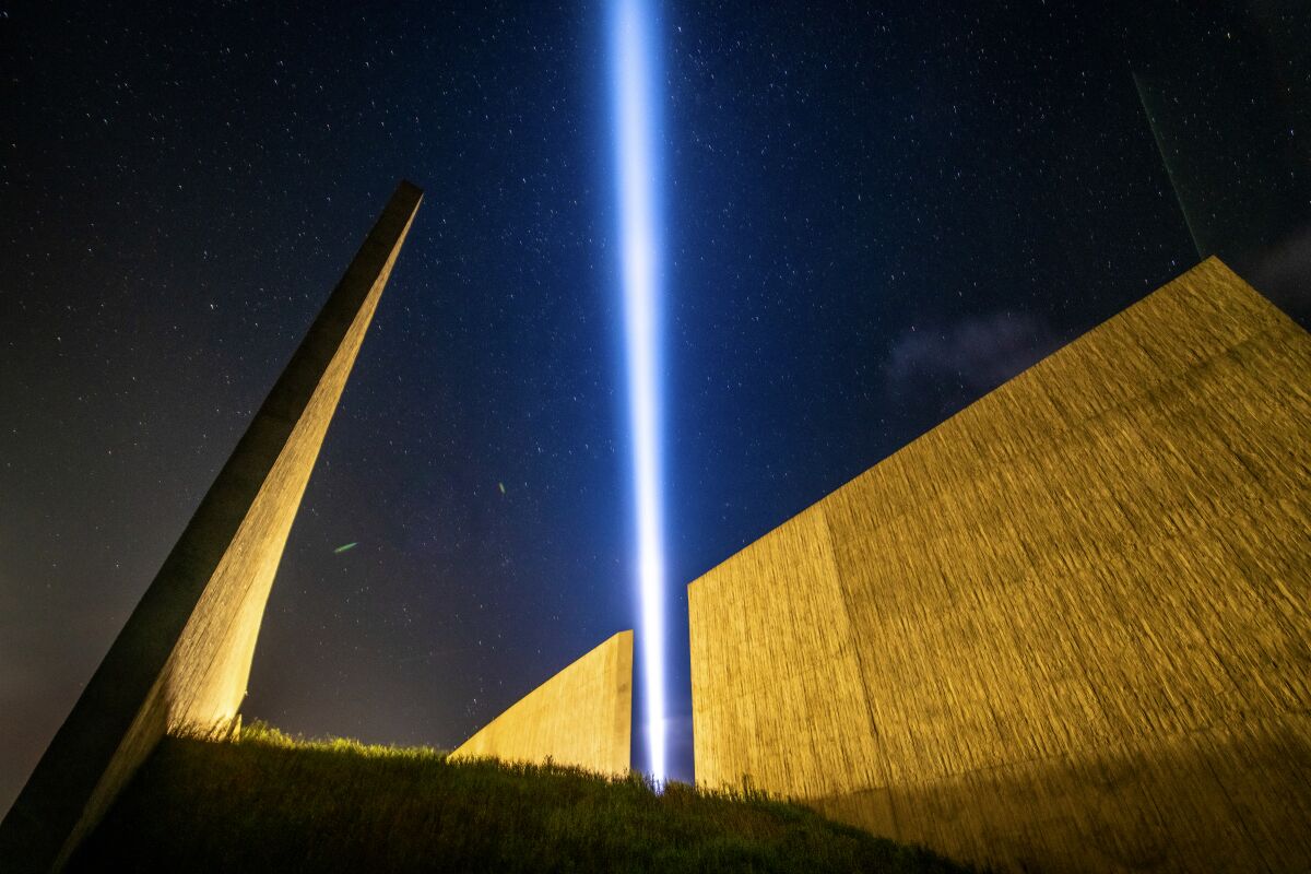 Beam of light shooting up in night sky among structures at the Flight 93 National Memorial