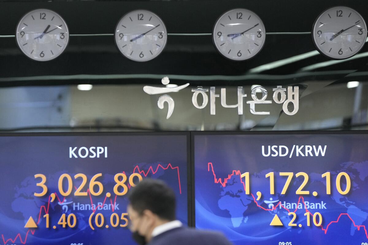 A currency trader walks by screens showing the Korea Composite Stock Price Index (KOSPI), left, and the foreign exchange rate between U.S. dollar and South Korean won at a foreign exchange dealing room in Seoul, South Korea, Thursday, Oct. 28, 2021. Asian shares fell Thursday after a retreat on Wall Street as banks and health care companies pulled the S&P 500 and the Dow Jones Industrial Average back from their latest record highs. (AP Photo/Lee Jin-man)