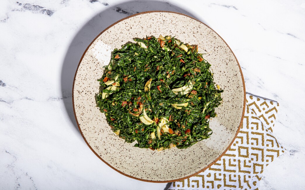 Thinly shredded collard green leaves are sautéed with tomatoes, garlic and ginger in this quick vegetable side dish.