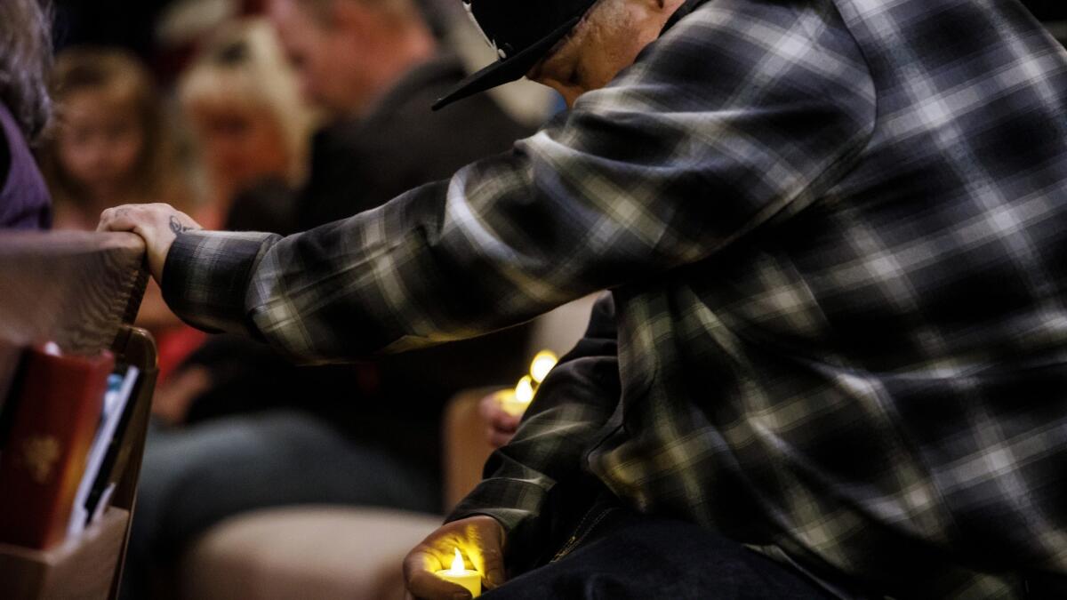 A man bows his head at a prayer vigil in Chico for those who died in the Camp fire.