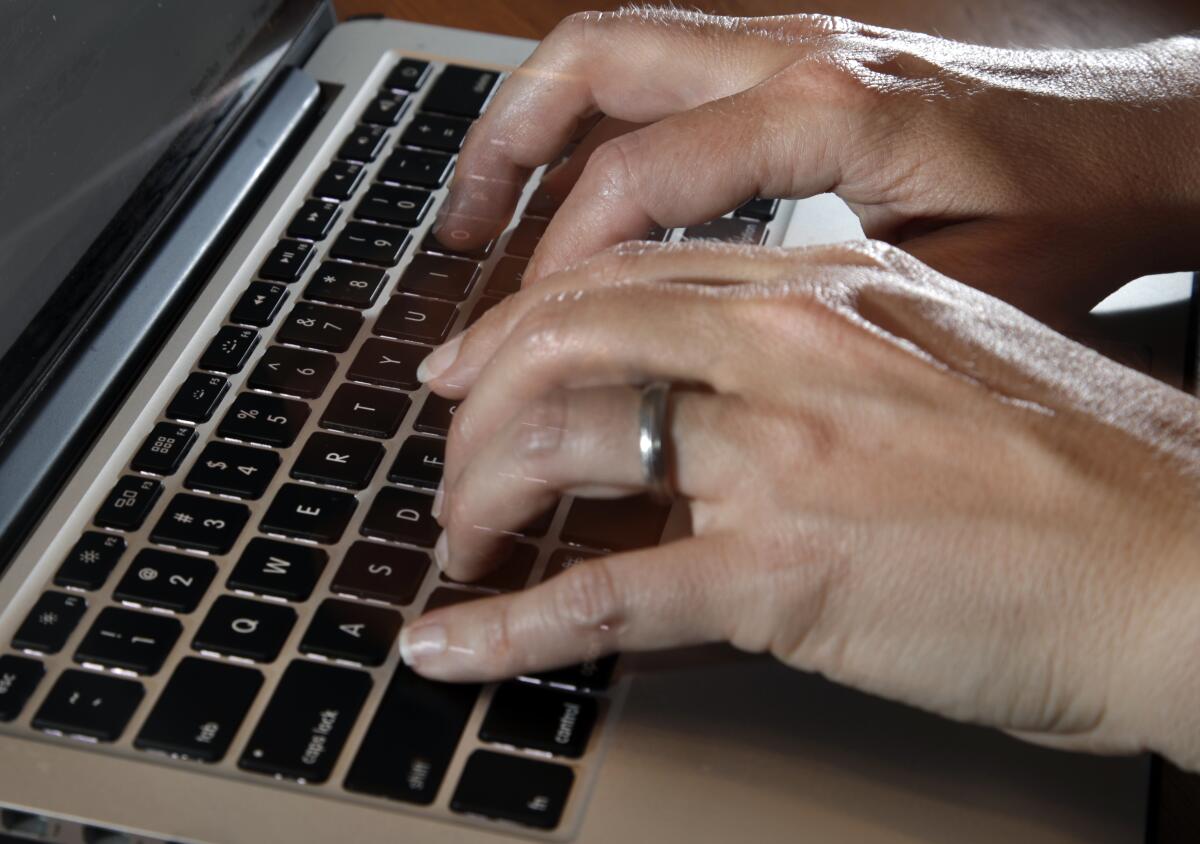 Closeup of hands typing on a laptop.