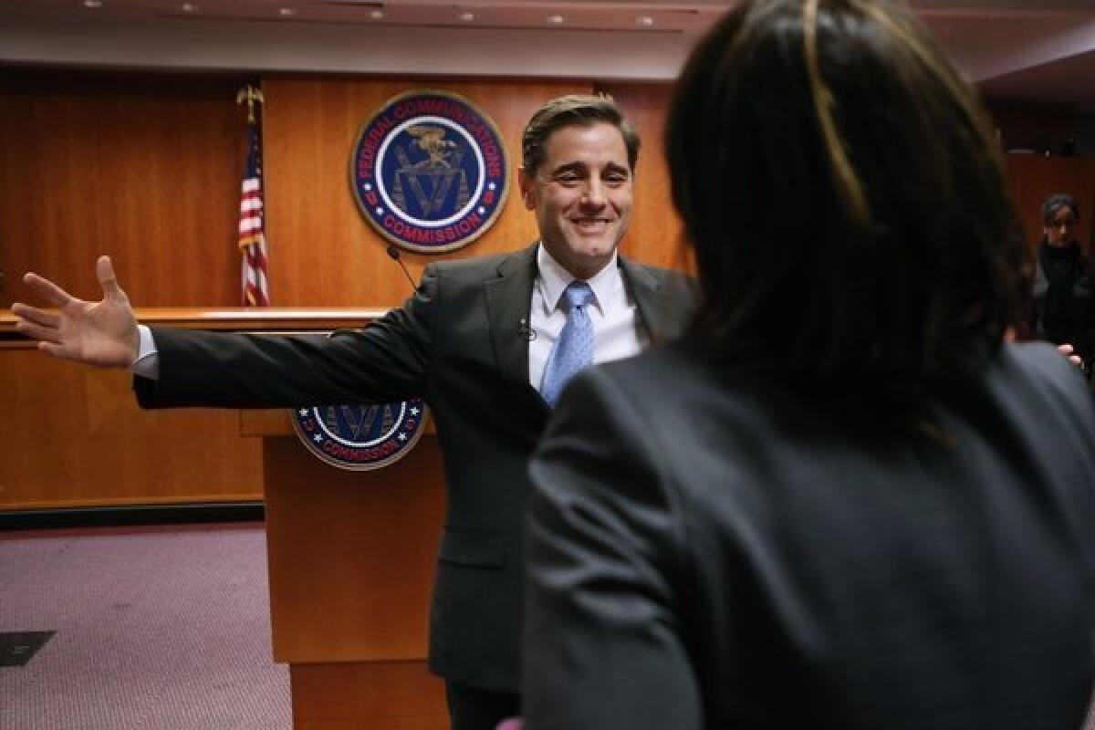 Federal Communications Commission Chairman Julius Genachowski embraces assistant Maria Gaglio after he announced he was stepping down.
