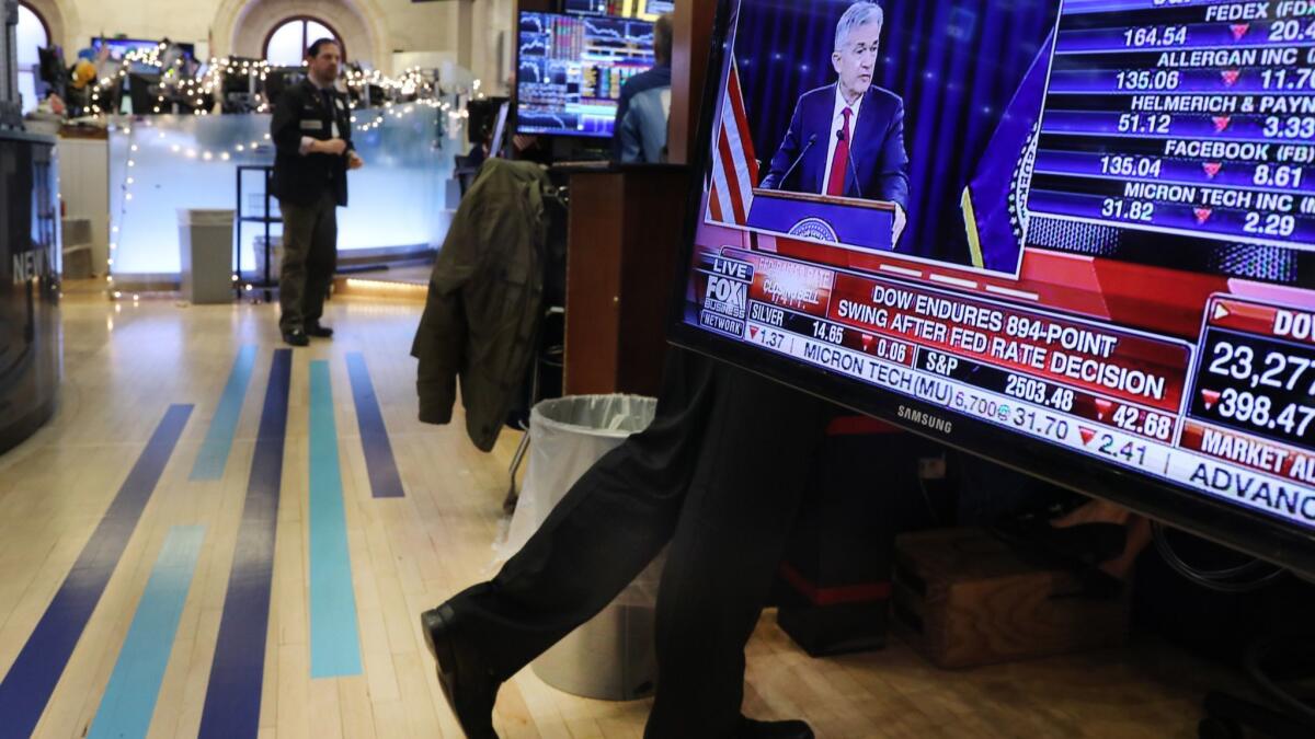 Traders work at the New York Stock Exchange as Federal Reserve Chairman Jerome H. Powell holds a news conference Dec. 19. Stocks' recent slide, driven by fears of a global slowdown. prompted traders to scale back expectations for interest-rate hikes — a buy signal for Treasuries.