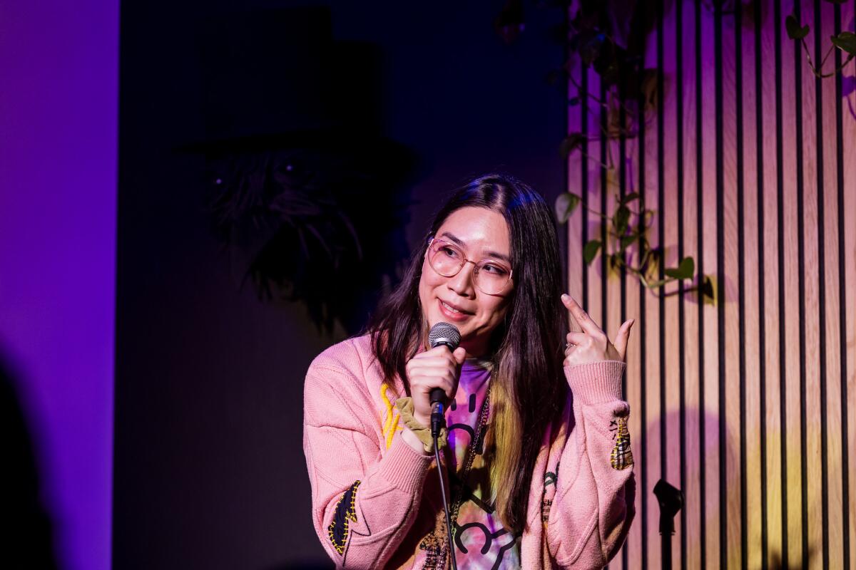Asian female comedian with glasses on stage