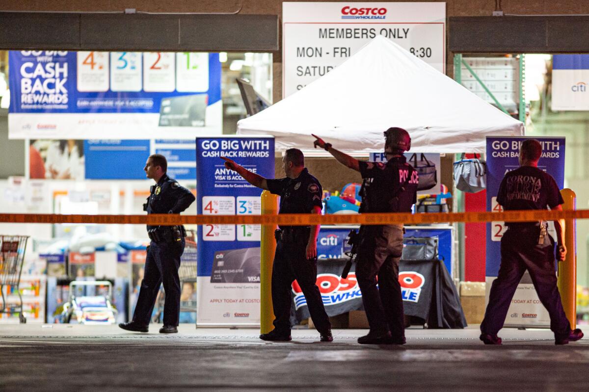 Police walk and point behind crime scene tape outside a Costco store