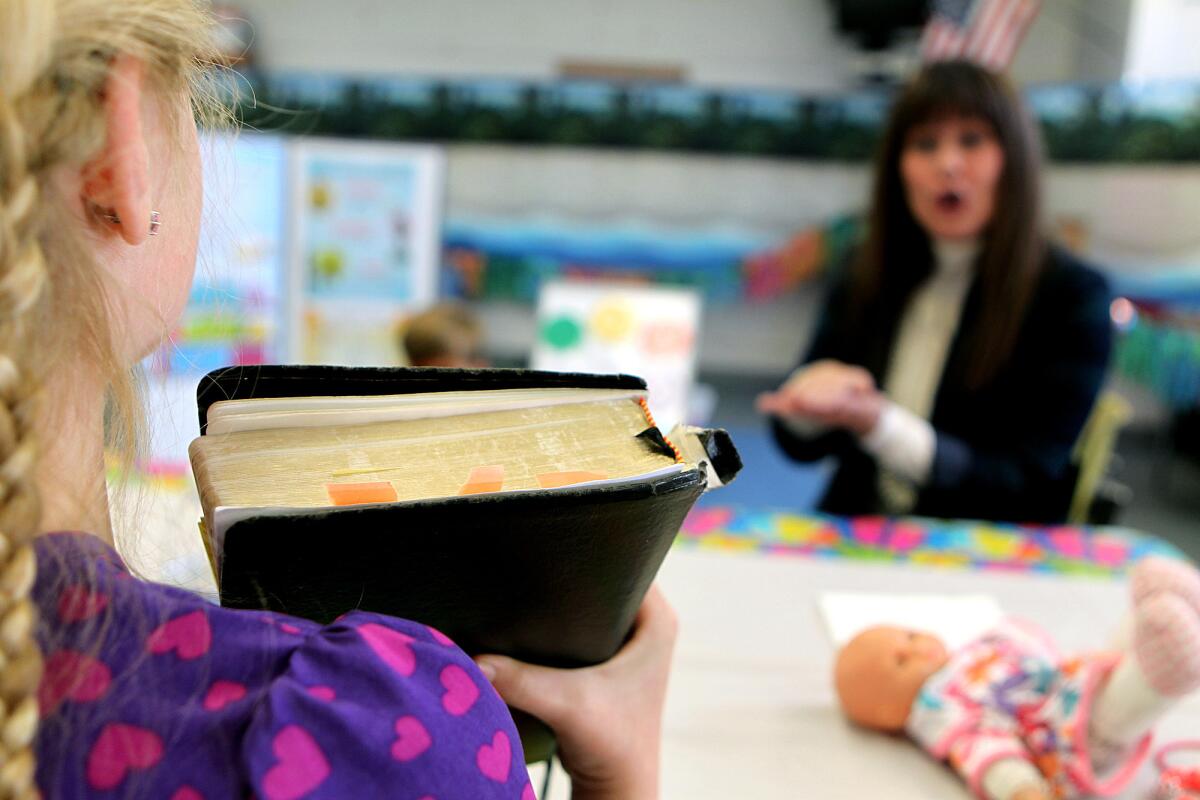 A child holds up a Bible during a Sunday school class in Santa Monica in 2014.