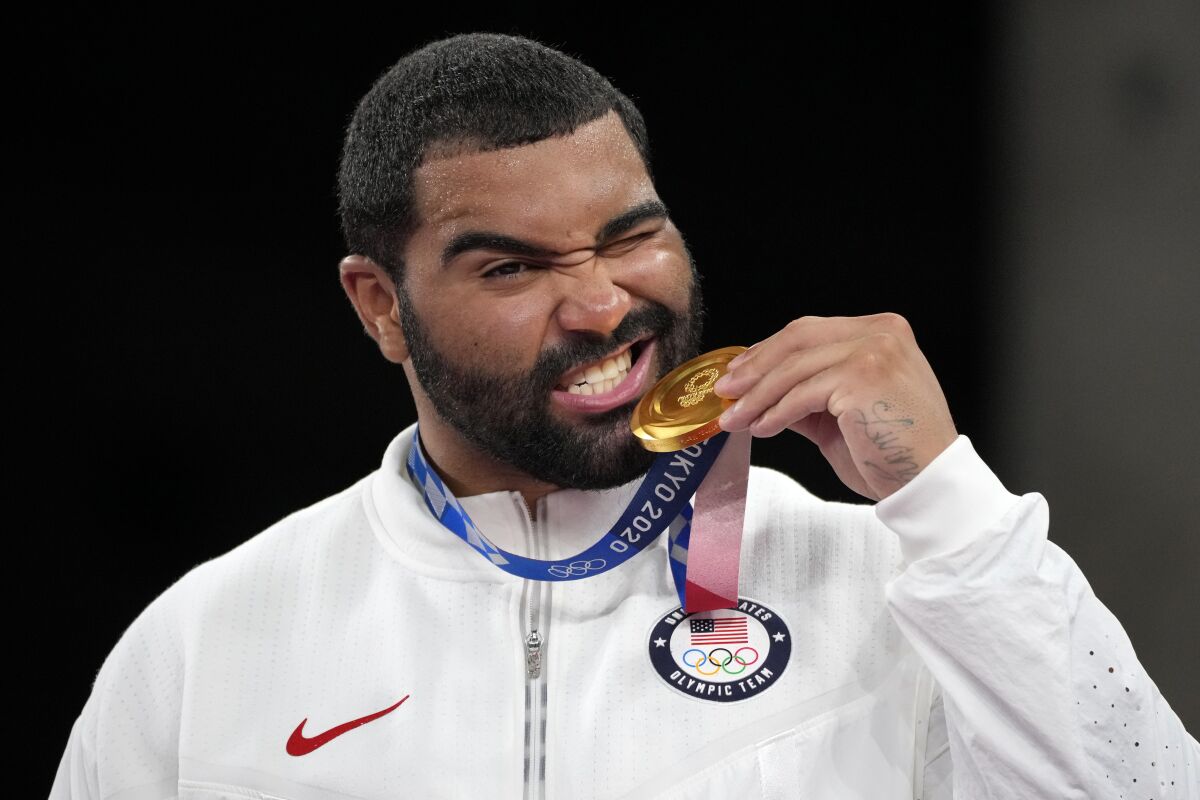 FILE - In this Aug. 6, 2021, file photo, United State's Gable Dan Steveson poses with his gold medal during the medal ceremony for the men's freestyle 125kg wrestling at the 2020 Summer Olympics, in Chiba, Japan. Steveson has achieved his childhood dream of signing with World Wrestling Entertainment, but with a twist. The WWE announced Thursday that it has signed Steveson to an exclusive NIL deal that will allow him to join the WWE roster and return to the University of Minnesota to defend his college heavyweight wrestling title. It is the WWE’s first NIL deal. (AP Photo/Aaron Favila, File)