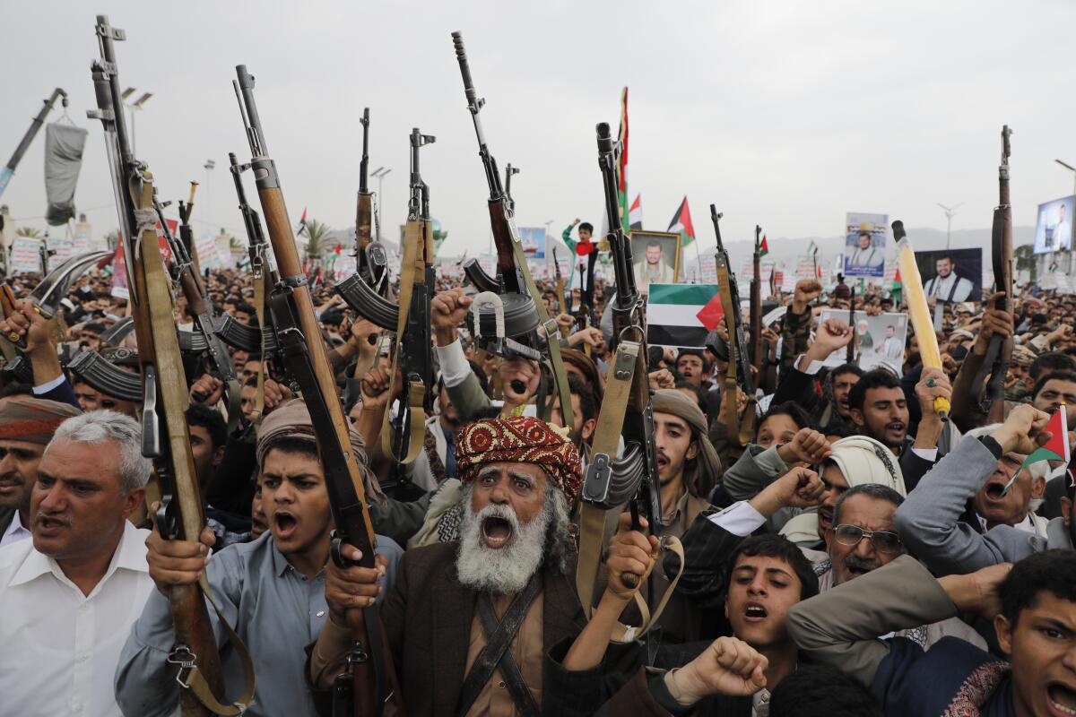 Houthi supporters attend a rally while holding up rifles.