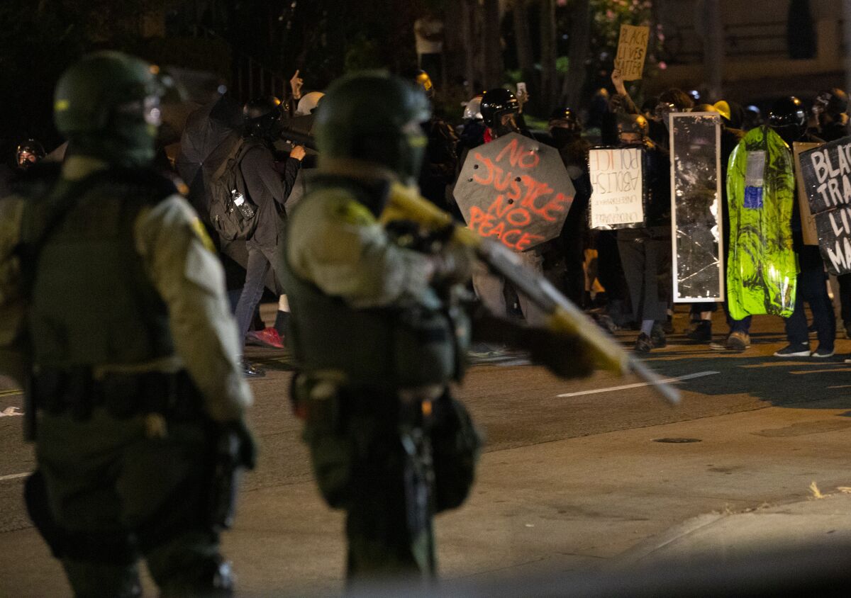 Los Angeles County sheriff's deputies watch a crowd of protesters.