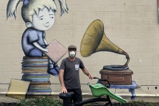 Carlsbad-based artist Bryan Snyder with his mural "Introducing Jingle" on an outside wall of Carlsbad Village Music.