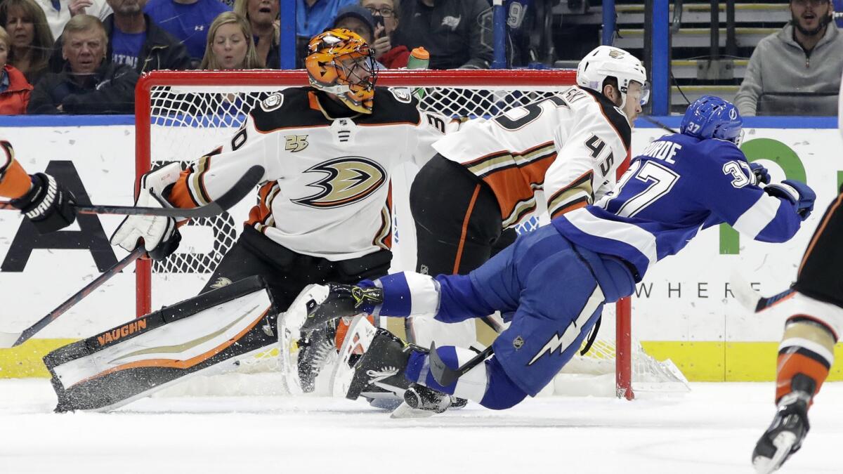 Ducks defenseman Andy Welinski (45) sends Tampa Bay Lightning center Yanni Gourde (37) flying after a check in front of goaltender Ryan Miller (30) during the first period on Tuesday.