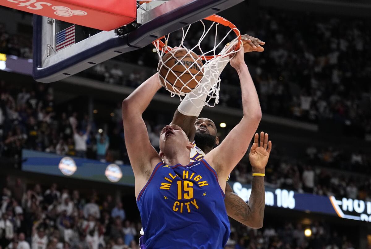 Nuggets center Nikola Jokic dunks in front of Lakers forward LeBron James 