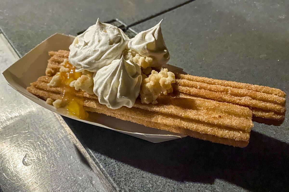 The Peach Cobbler Churro topped with peaches, whipped topping and streusel