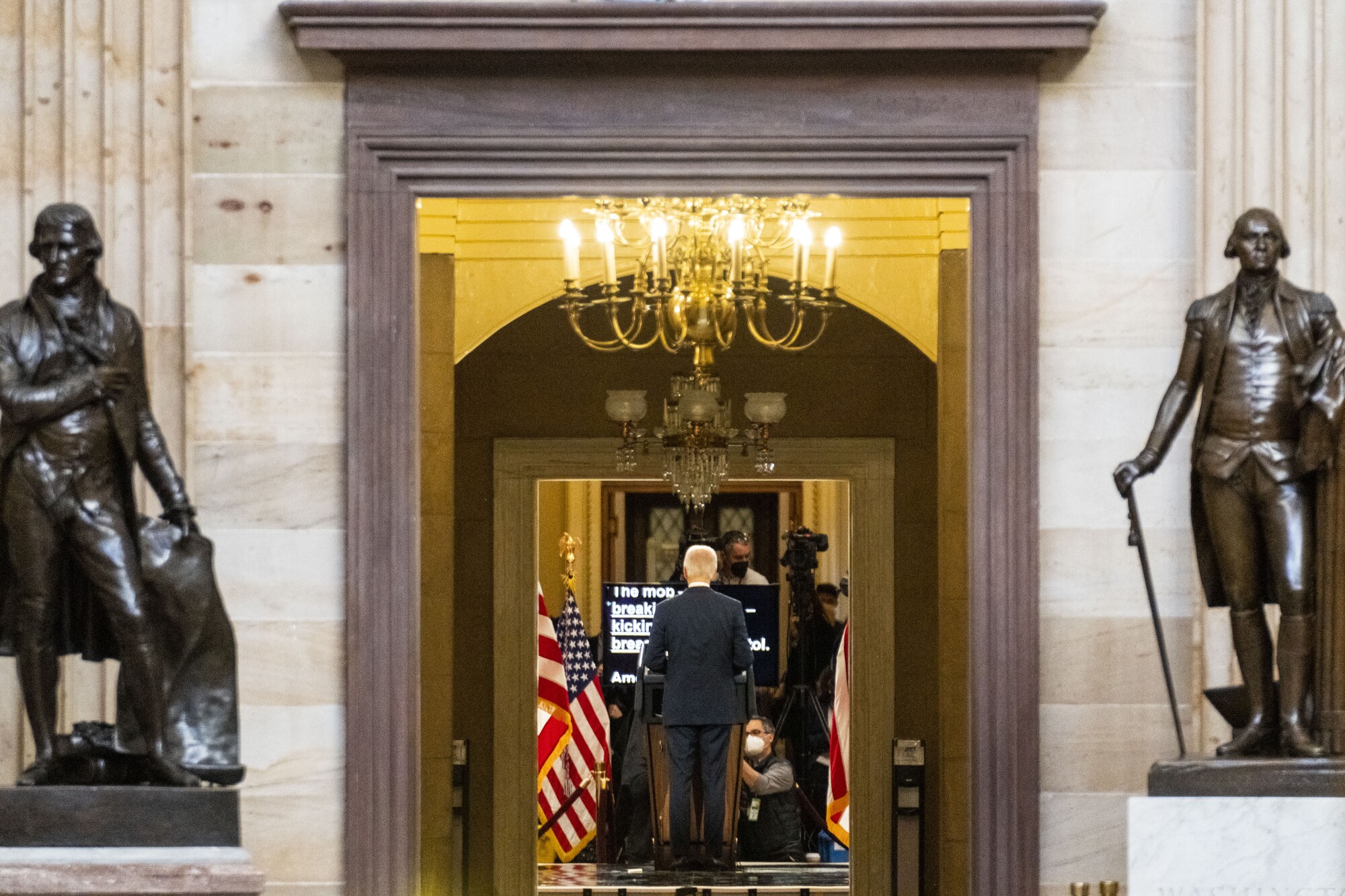 President Biden, seen from behind, delivers remarks from Statuary Hall at the U.S. Capitol