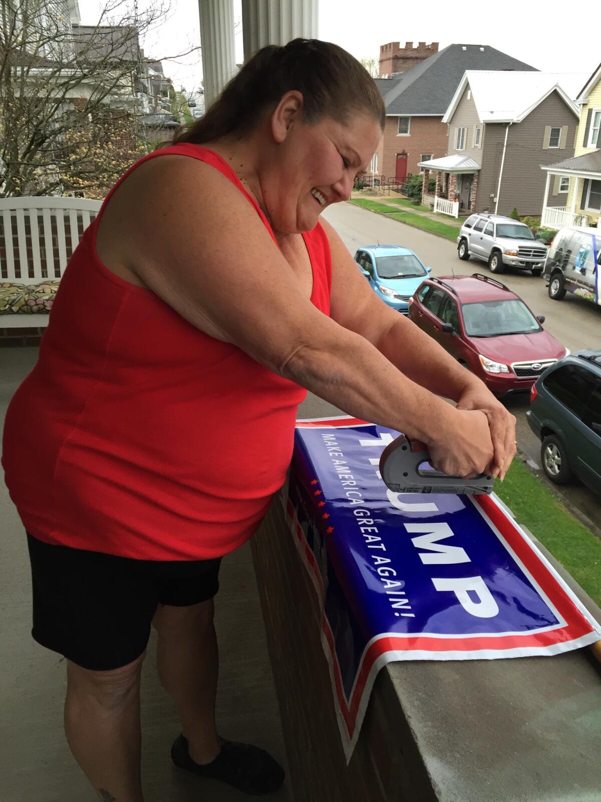 Laurie McGinnis on the porch of her home working on a Trump poster. (Lisa Mascaro / Los Angeles Times)