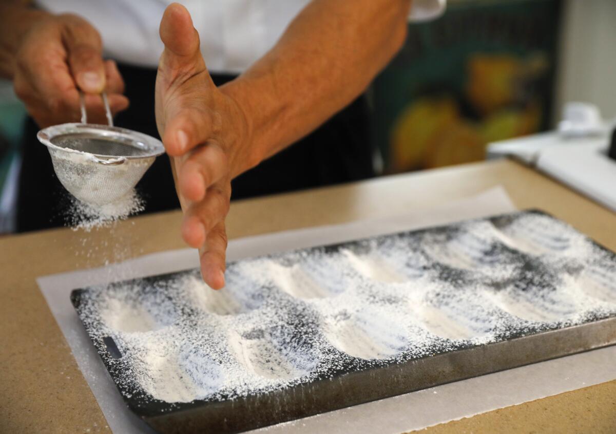 Chef Bruno Albouze sifts flour onto a madeleine form before tapping out the excess flour and applying the batter.