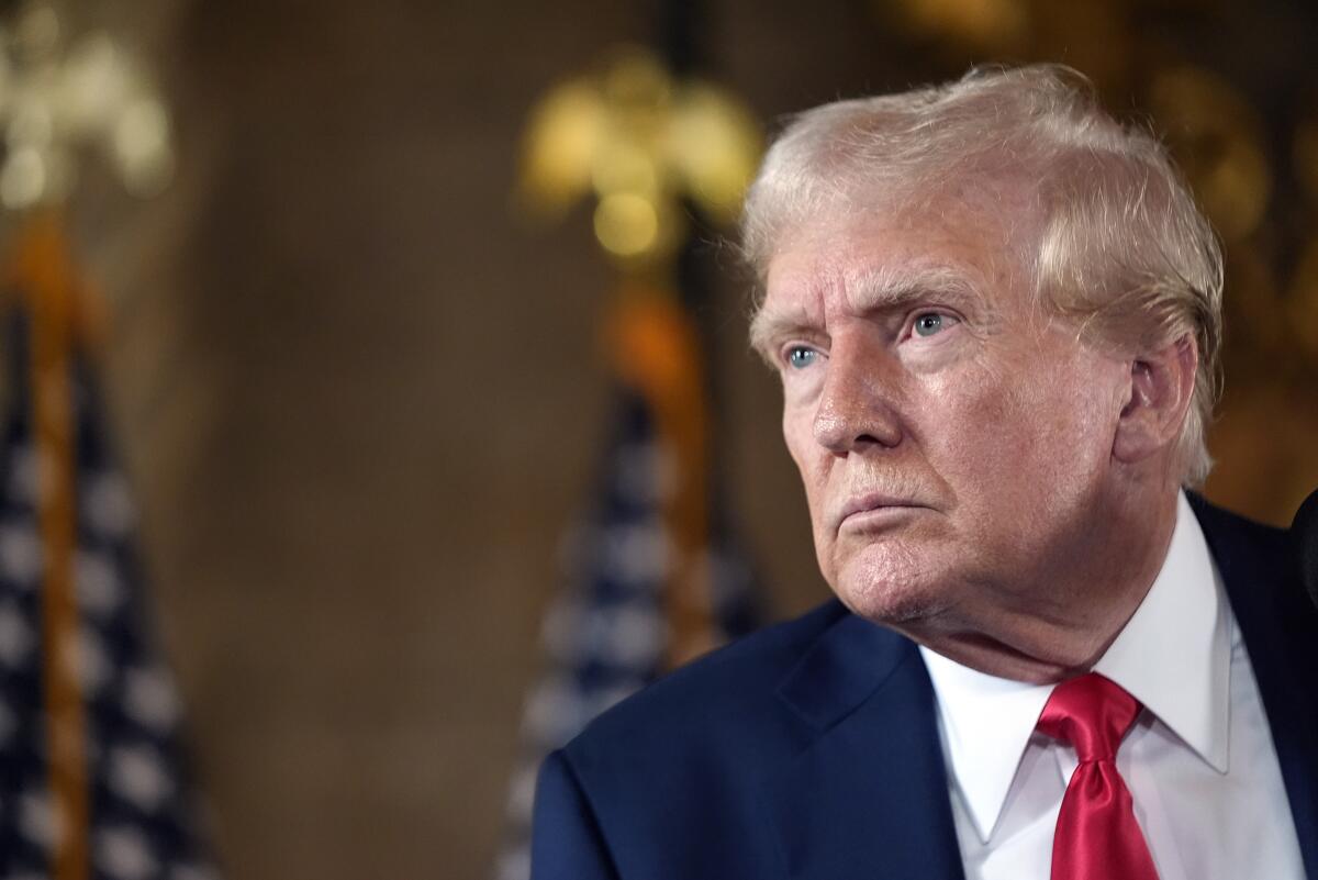 Former President Trump listens at a news conference.