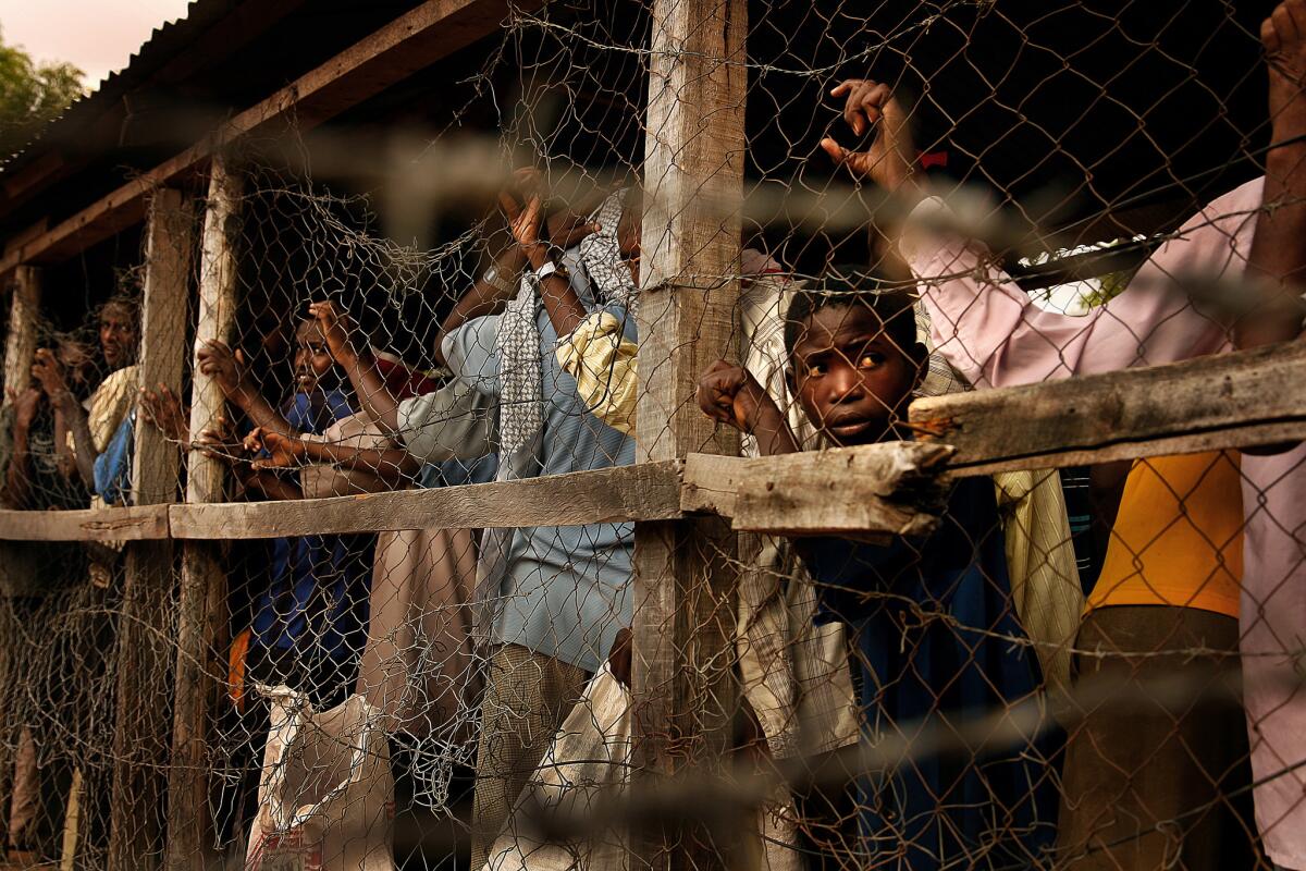 People lined up to receive food are funneled through tunnels similar to cattle chutes. Through openings at various intervals, aid workers scoop wheat flour, cornmeal, dried peas, soy protein powder and salt into the refugees' gunnysacks.