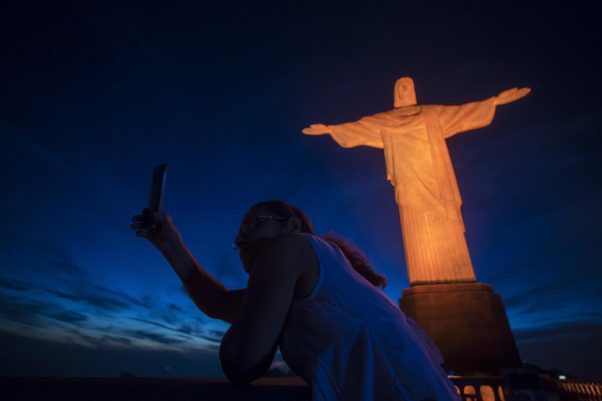 A tourist takes a selfie with the Christ the Redeemer statue in Rio de Janeiro.