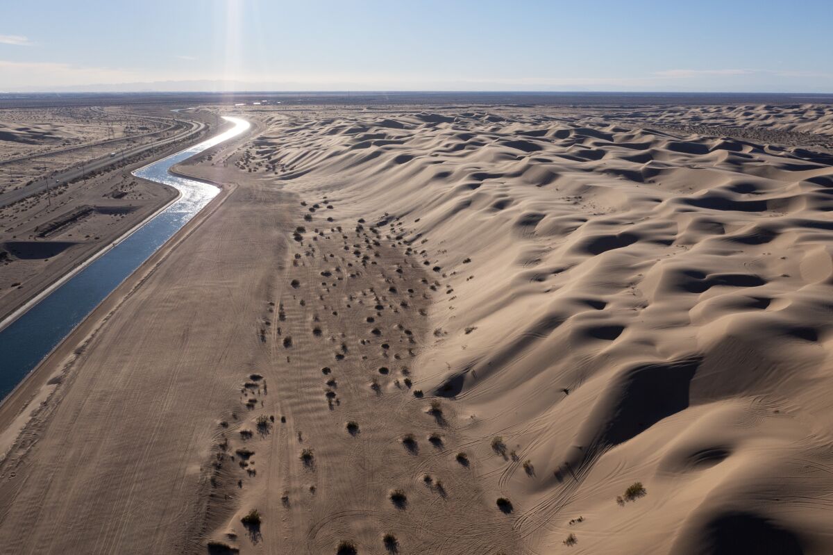 Overhead view of a narrow canal surrounded by desert sand.