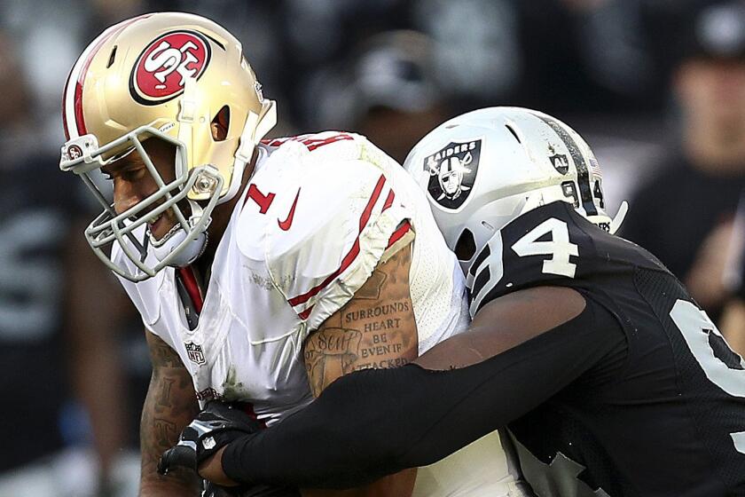 San Francisco 49ers quarterback Colin Kaepernick, left, is sacked by Oakland Raiders defensive tackle Antonio Smith during the second half of the Raiders' 24-13 win Sunday.