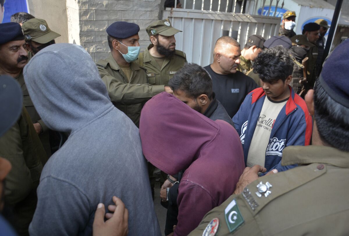 FILE - Police officers escort suspects allegedly involved involved in the killing of Priyantha Kumara, a Sri Lankan factory manager, after their appearance in anti-terrorism court, in Gujranwala, Pakistan, Dec. 6, 2021. A defense lawyer said Monday, April 18, 2022, that a court in Pakistan’s eastern city of Lahore has sentenced six people to death and handed down life imprisonment to nine others after finding them guilty of involvement in last year’s vigilante killing of Kumara whose body was publicly burned over an allegation of blasphemy. As many as 73 suspects were also awarded jail terms from two to five years each by the court. (AP Photo/Aftab Rizvi, File)