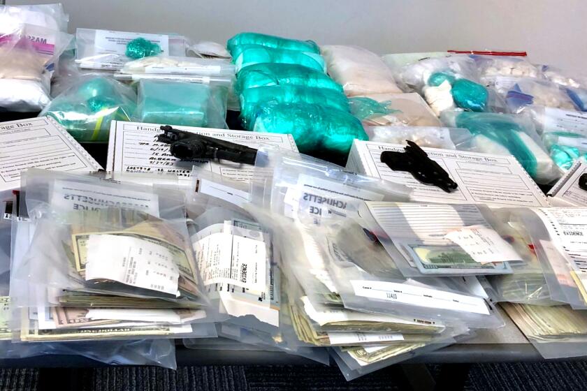 In this photo provided by the Massachusetts State Police, a selection of drugs, handguns, cash and other items are displayed as evidence following law enforcement raids in Boston, Thursday, June 20, 2019. Officials say multiple people were arrested and drugs worth millions were seized in the bust of a major drug trafficking ring. Massachusetts Attorney General Maura Healey said Thursday it's the biggest takedown of a major opioid trafficking operation in the history of her office. (Massachusetts State Police photo via AP)