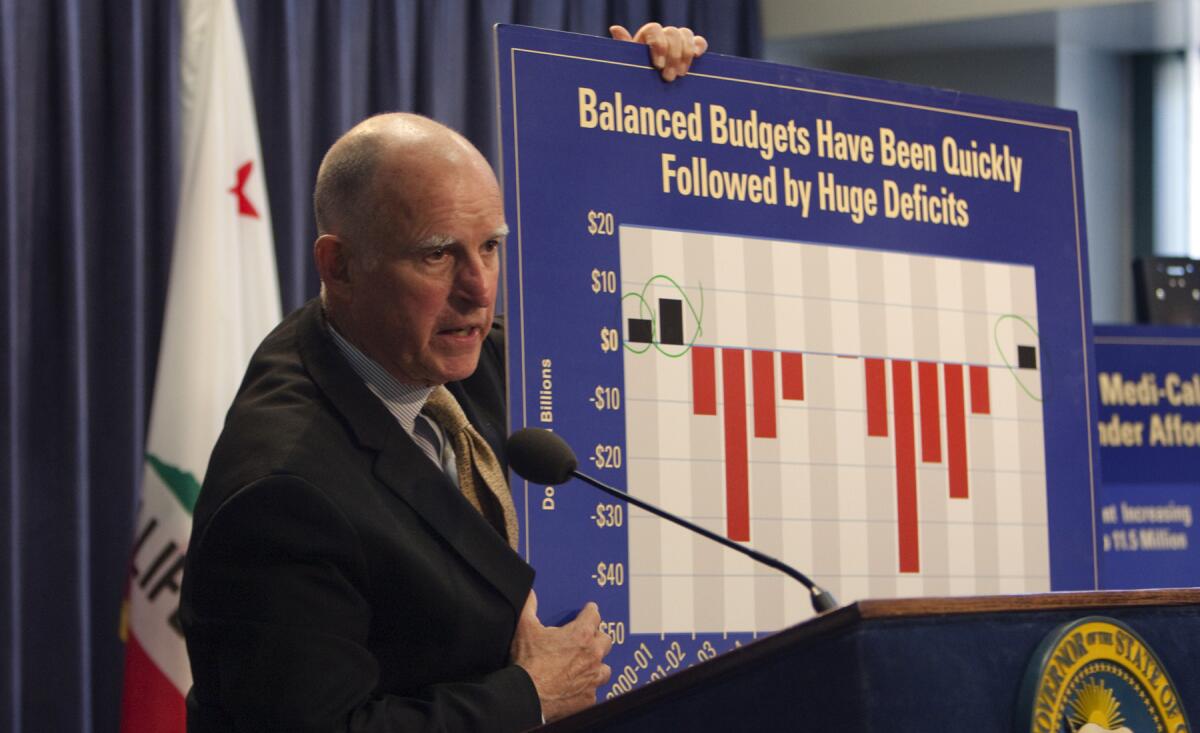 Gov. Jerry Brown holds a poster showing that balanced state budgets have been followed by huge deficits in previous administrations while discussing his revised 2014-15 budget proposal during a news conference in Los Angeles earlier this week.