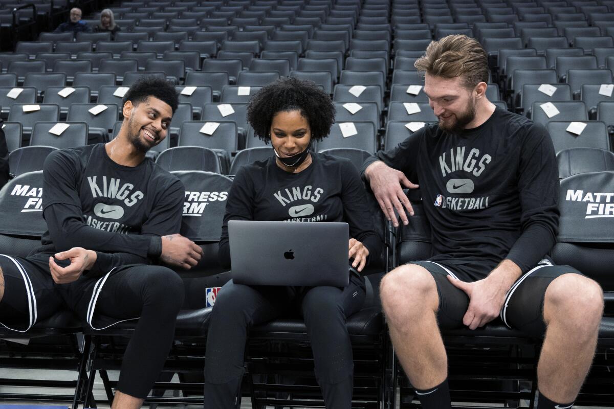 Kings assistant coach Lindsey Harding, center, reviews video with Domantas Sabonis, right, and Jeremy Lamb in 2022.