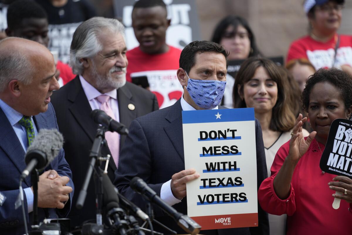 Rep. Trey Martinez Fischer holds a sign that says Don't Mess With Texas Voters as he and others join a rally
