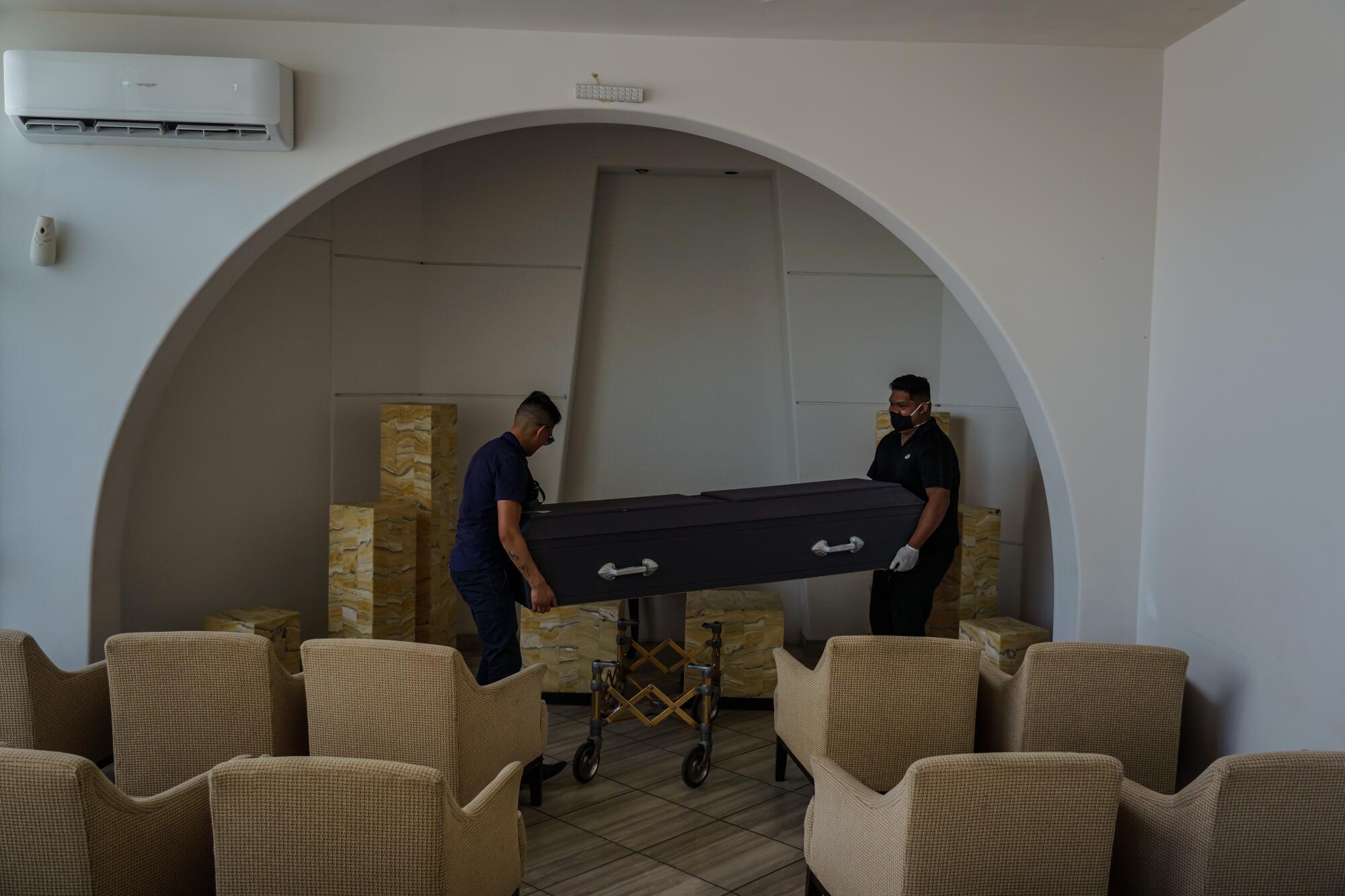 Funeral home workers prepare a casket for transport to the cemetery at the San Ramon Funeral home in Tijuana, Mexico, on April 28, 2020.
