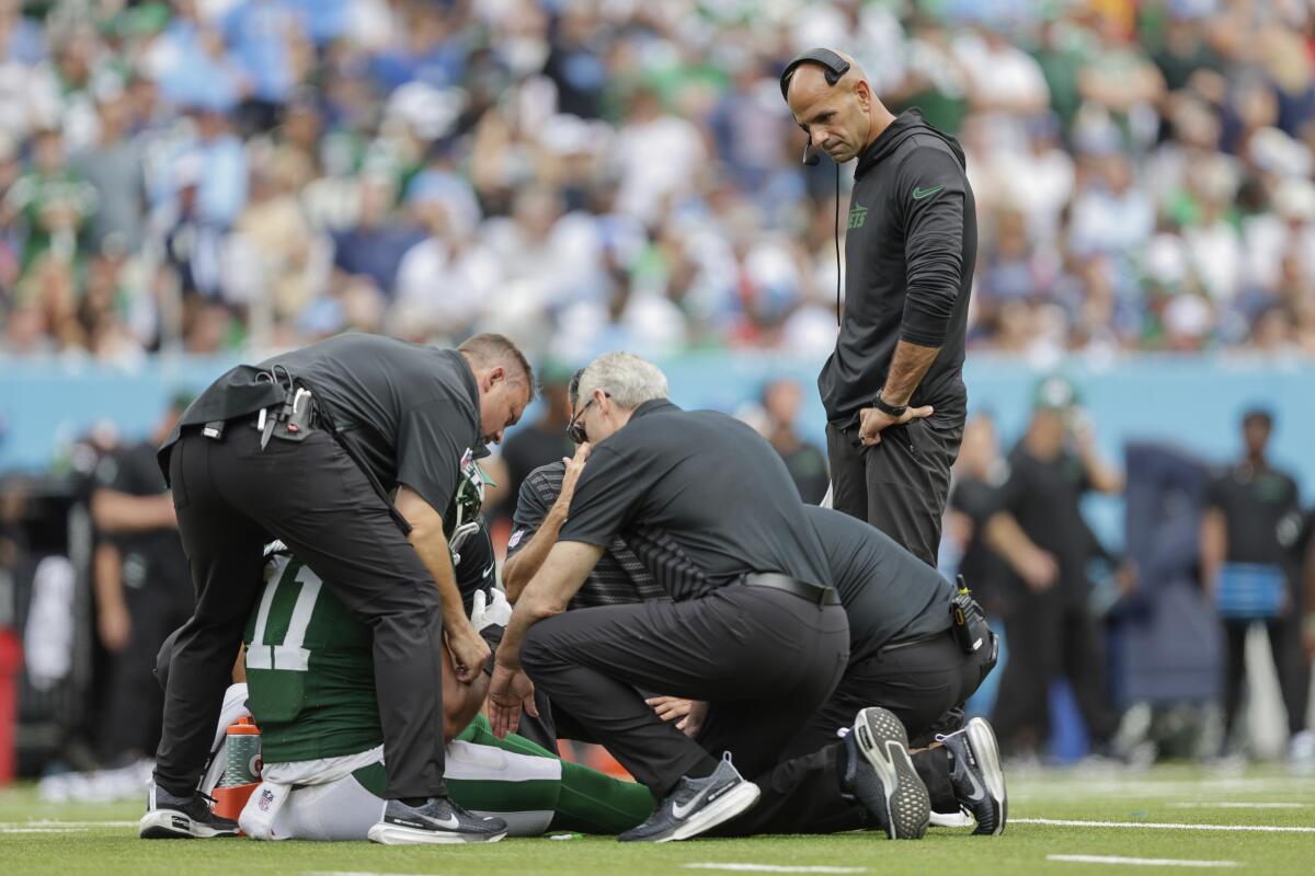 Jets linebacker Jermaine Johnson (11) is examined by the medical staff as coach Robert Saleh (right) watches.