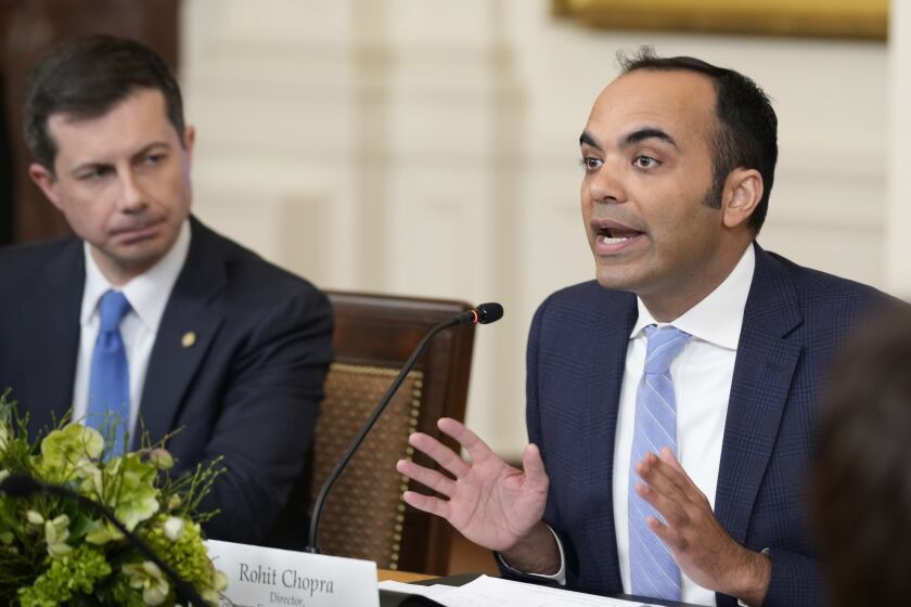 FILE - Rohit Chopra, right, director of the Consumer Financial Protection Bureau, speaks while Transportation Secretary Pete Buttigieg, left, listens as President Joe Biden, not pictured, meets with his Competition Council on the economy and prices in the East Room of the White House, Feb. 1, 2023, in Washington. Banks will need to start reporting the demographics and income of small business loan applicants under new rules published by the Consumer Financial Protection Bureau on Thursday, March 30, 2023. (AP Photo/Andrew Harnik, File)