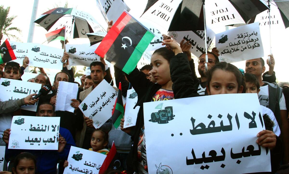 Libyans protest a months-long militia blockade of vital oil terminals during a Dec. 13 demonstration in the capital, Tripoli. The bodies of two foreign teachers, one from Britain and one from New Zealand, were found Thursday at one of the gas facilities subject to the blockade, near the western coastal town of Sabratha. No motive for the shooting deaths was immediately apparent, authorities said.