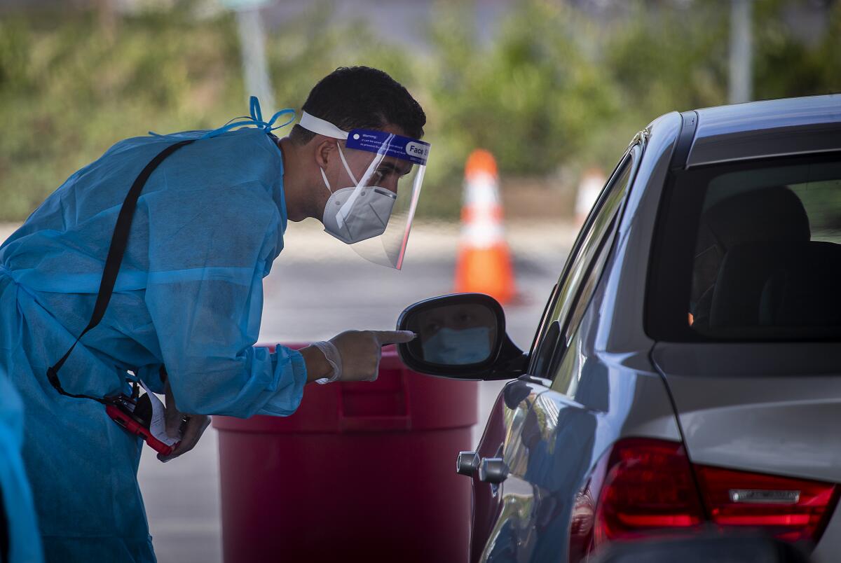 A healthcare worker talks with a motorist at the drive-through COVID-19 testing site in Costa Mesa.