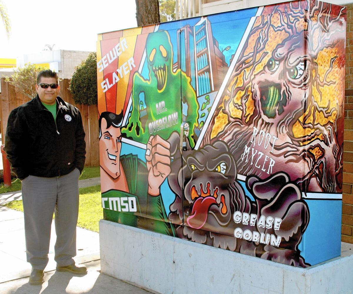 Costa Mesa Sanitary District's Steve Cano, a maintenance supervisor, stands next to a pump station on Wilson Street with Sewer Slayer, a superhero-like character he helped create that teaches children about how the district keeps the sewers running, and its various villains.