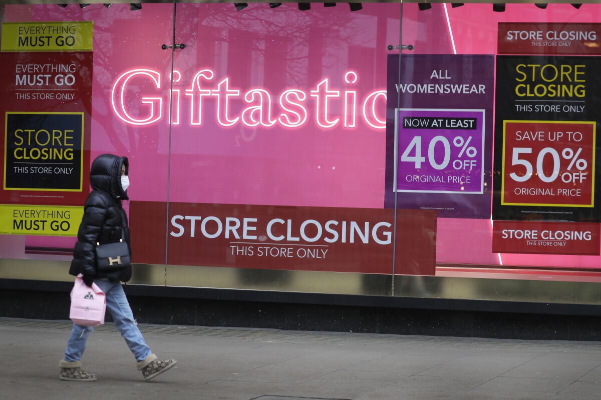 A woman walks past windows of a closed shop on Oxford Street in London on Saturday.