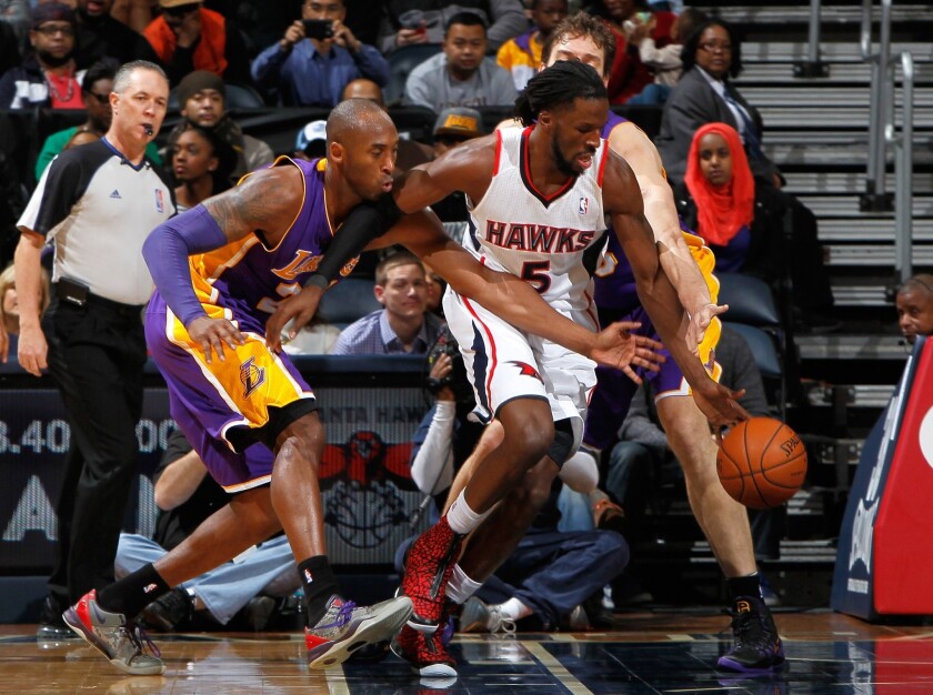 Kobe Bryant tries to steal the ball away from Atlanta's DeMarre Carroll during the first half of Monday's 114-100 loss to the Hawks. Pau Gasol has a hand in the play from behind Carroll.