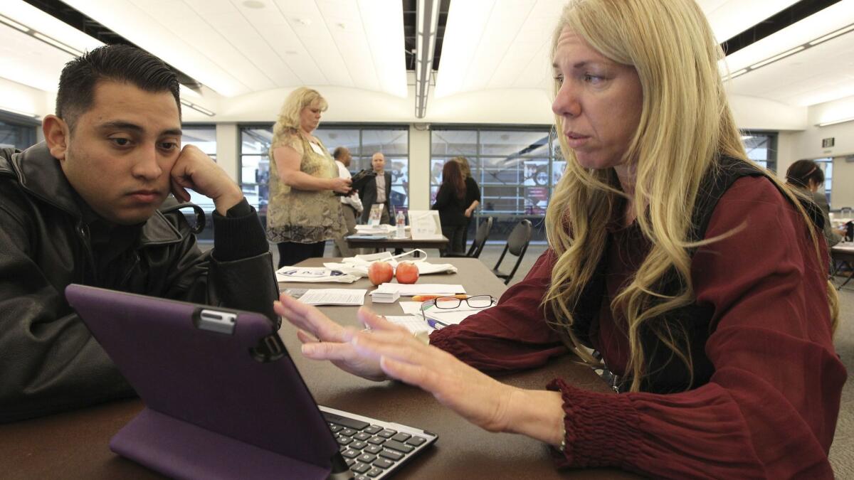 Healthcare reform specialist Naama Pozniak, right, helps Edgar Loya compare plans at an Affordable Care Act enrollment fair at Pasadena City College in 2013. The Trump Administration's new actions to dismantle the healthcare law may hit a legal roadblock in California.