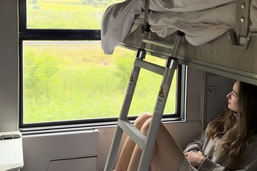 Sarah Marks, of London, looks out at the Italian countryside on TrenItalia's Intercity Notte sleeper train from Palermo to Rome, on June 10, 2023. A growing number of climate-conscious Europeans are giving up flying in favor of long-haul trains. (Sarah Marks via AP)
