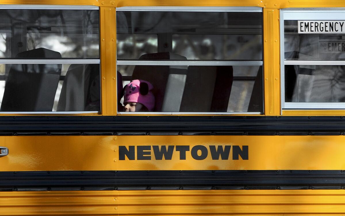 A child sits on a Newtown bus leaving the new Sandy Hook Elementary School on the first day of classes in Monroe, Conn.