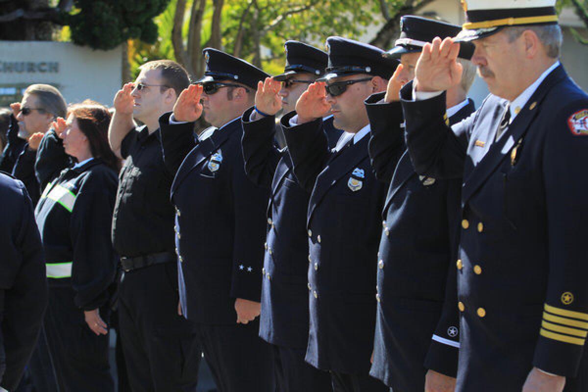 Oakland firefighters salute during funeral services Tuesday for paramedic Quinn Boyer at St. Theresa Catholic Church in Oakland.