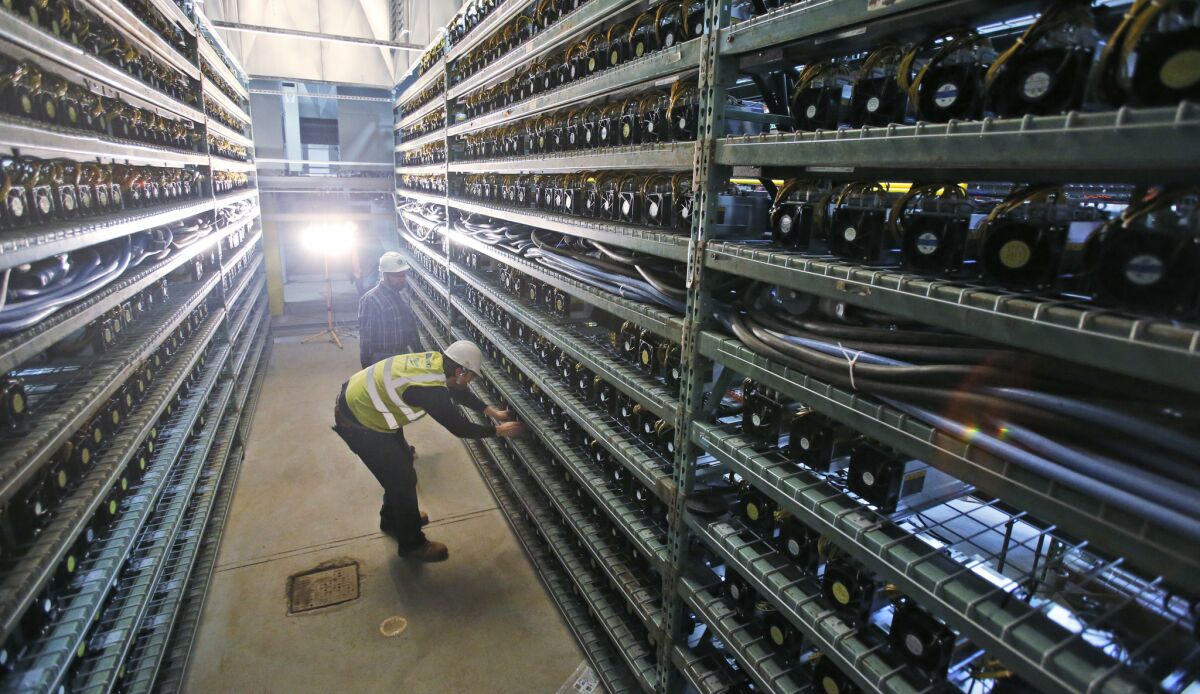 Workers look over racks of bitcoin data miners during construction of a data center in Virginia Beach, Va.