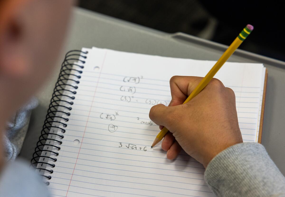 A student takes notes during a lecture in a college algebra class.